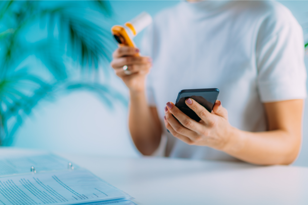 Person performing a spirometry test for Asthma or COPD while referring to their phone.